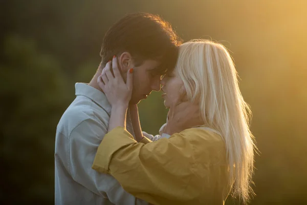 Smyslní milenci objímající a líbající se při západu slunce. Mladá smyslná přítelkyně ráda vášnivě políbí svého přítele. Hezký mladý muž objímá svou ženu a polibky. — Stock fotografie