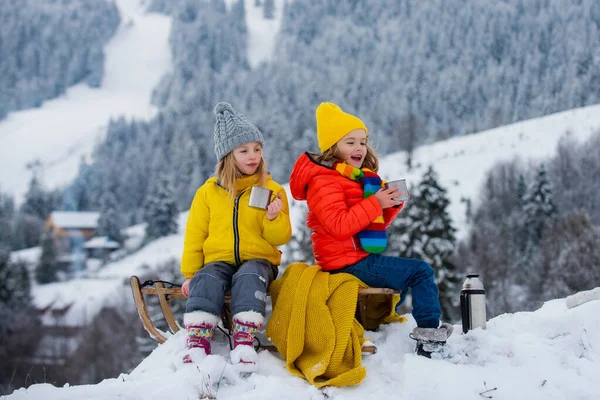 Mutlu küçük oğlan ve kız kışın kızak kayıyor. Çocuklar kışın kar kayaklarında kayıyor. Oğlu ve kızı kızakla gezintiye çıkıyor.. — Stok fotoğraf