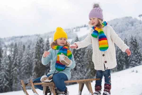 Luge garçon et fille dans une forêt enneigée. Hiver plein air enfants amusant pour Noël et le Nouvel An. Les enfants profitent d'une promenade en traîneau. Enfants d'hiver amusant. — Photo