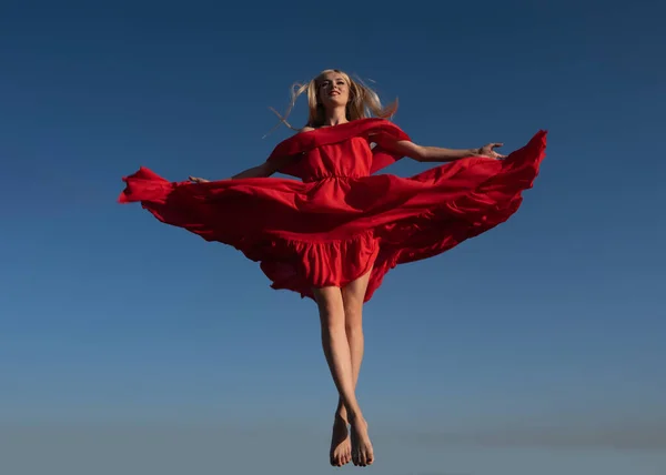 Chica del movimiento en vestido rojo en el cielo. Mujer atractiva en traje de moda afuera. Foto de moda al aire libre de joven hermosa dama disfrutando de la primavera. — Foto de Stock
