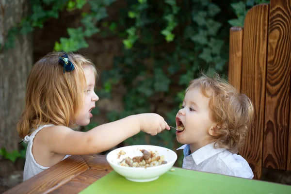 Cibo per bambini carino, bambini che mangiano. Sorellina che dà da mangiare al bambino. Buon appetito. — Foto Stock