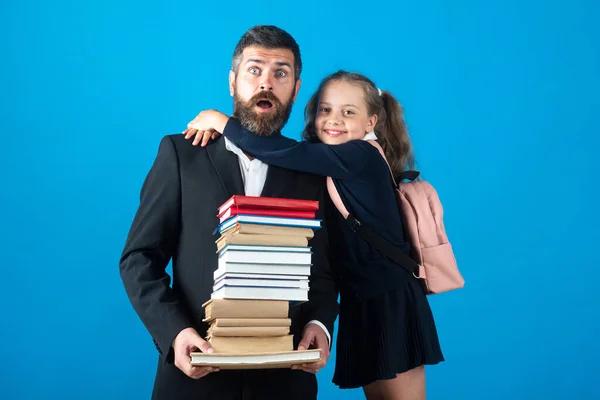 Grundschüler umarmt Lehrerin im Atelier. Vater oder Lehrer mit Tochter halten große Stapel Schulhefte in der Hand. Lehrertag. — Stockfoto