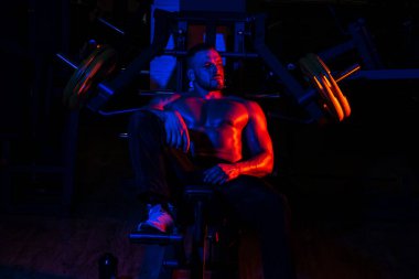 Eğitimden sonra yorgun sporcu dinleniyor. Bir şişe suyu ve proteini olan bir adam. Güçlü erkek, çıplak gövdesi var..