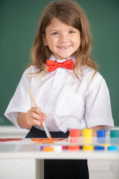 Χαριτωμένο κοριτσάκι που ζωγραφίζει στο σχολείο. Ζωγραφίζει ένα κορίτσι στο δημοτικό. Πορτρέτο του μικρού κοριτσιού χαμογελώντας ευτυχισμένα απολαμβάνοντας τέχνη και τέχνη μάθημα σχεδίασης. — Φωτογραφία Αρχείου