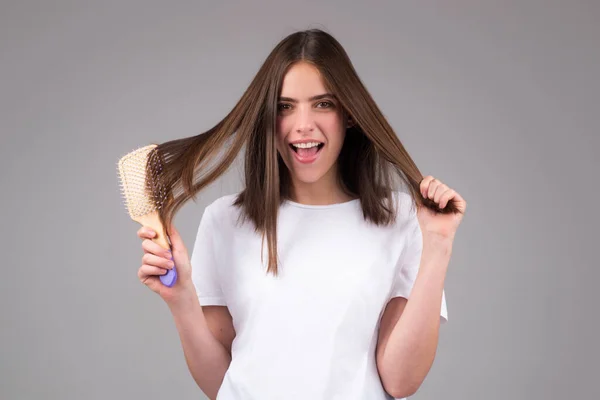 Žena dělá účes s hřebenem. Krásná mladá žena drží zdravé a lesklé vlasy, studio. Detailní záběr na mladé ženy česání vlasů. — Stock fotografie