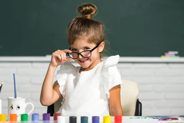 Bonito cara menina da escola com óculos. Meninas desenhando um colorido imagens com lápis lápis lápis na sala de aula da escola. Pintura crianças. — Fotografia de Stock