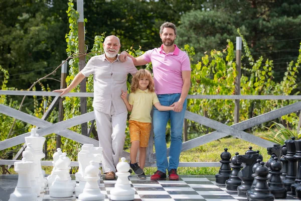 Porträt von Großvater Vater und Sohn beim Schachspielen. Glückliche Männer in verschiedenen Altersgruppen beim Schachbrettspiel. Generation der drei Männer. — Stockfoto