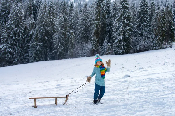 Chlapec sáňkaří v zimě. Děti jezdí na sněhových skluzavkách v zimě. — Stock fotografie
