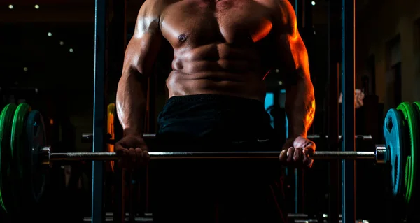 Hombre musculoso haciendo bíceps levantando la barra. Hombre muscular haciendo ejercicio en el gimnasio haciendo ejercicios, fuertes abdominales masculinos desnudos del torso. —  Fotos de Stock