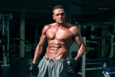 Spor salonundaki adam. Kaslı ve güçlü adam egzersiz yapıyor. Sporcu ağırlıklarla egzersiz yapıyor. Fitness ve Crossfit.