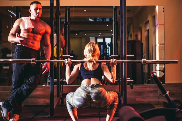 Giovane allenamento sportivo di coppia con bilanciere in palestra. Allenatore muscolare uomo formazione donna Personal trainer istruttore di fitness. — Foto Stock