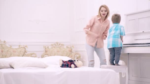 Moeder met zoontje die in het weekend samen in bed speelt, goedemorgen. Moederschap en ouderschap, gelukkige jeugd. — Stockvideo