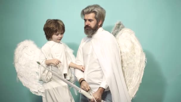 Η ιδέα του Αγίου Βαλεντίνου. Άγγελοι πατέρας και γιος cupid στοχεύοντας με τόξο και βέλος. Γονέας, γονιός με παιδί αγόρι, παιδική ηλικία. — Αρχείο Βίντεο