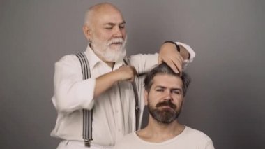 Profesyonel kuaför berber dükkanındaki sakallı adamın saçını tarıyor. Berber berber dükkanında çekici bir adamın saçını kesiyor..