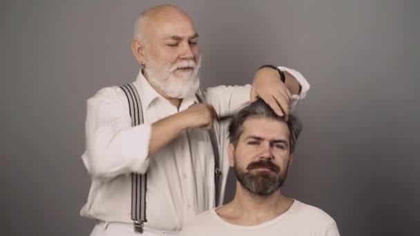 Coiffeur professionnel peigne les cheveux de l'homme barbu dans le salon de coiffure. Barbier faire coupe de cheveux à l'homme attrayant dans le salon de coiffure. — Video