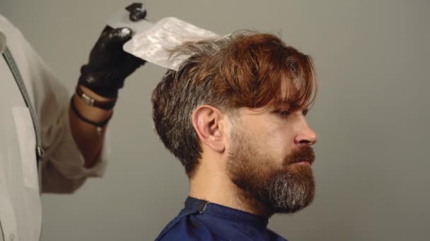 Friseursalon, Haarfärber. Prozess eines Mannes, der sich beim Friseur die Haare färben lässt. Schönheit und Menschen. Stylist Mann mit Haarfärbung und Pinsel Haare färben im Salon. — Stockvideo
