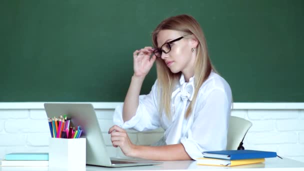 Journée des professeurs. Joyeux souriant enseignante avec ordinateur portable au tableau noir. Femme pigiste de bonne humeur à l'aide d'un ordinateur portable. — Video