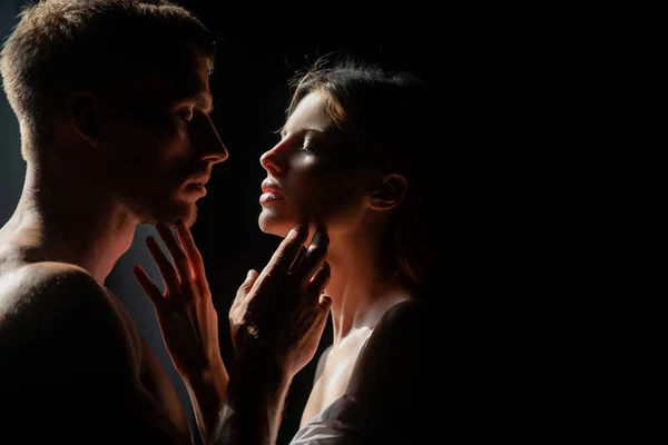 Hermosa pareja amorosa posando sobre fondo oscuro con luces nocturnas. Sensual retrato de una sexy pareja abrazando mientras citas. Pareja joven enamorada de negro. El encantador coupl pasa tiempo juntos. — Foto de Stock