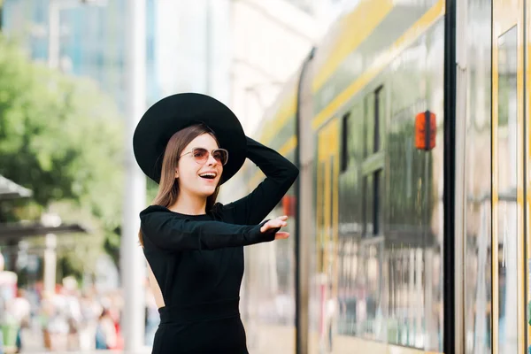 Bonito modelo feminino correndo atrás de ônibus trolleybus na cidade de verão na Europa. Mulher na moda posando no fundo da rua. Viajar na cidade. — Fotografia de Stock