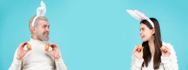 Paskalya yumurtalı Paskalya ailesi. Tatillerde. Aile Paskalyayı kutlar. Paskalya için yumurtalı bir çift. Tavşan kulaklı mutlu çift. Komik tavşanlı pankart, kopyalama alanı.