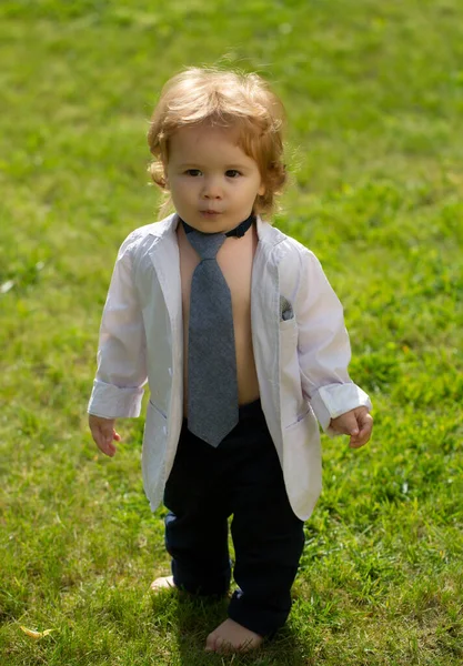 Fashion baby child enjoy the summer on the nature in the park outdoor. Funny little man in suit, jacket and necktie. — Stockfoto