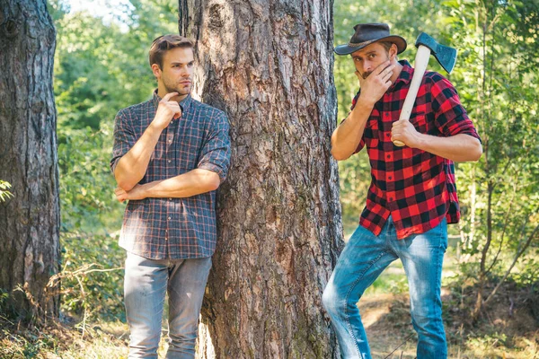 Leñadores leñadores. Hipsters hombres en serio cara con hacha. Lumberjack brutal y barbudo sostiene hacha. Dos leñadores en el bosque. El hombre con sombrero se ve brutalmente. —  Fotos de Stock