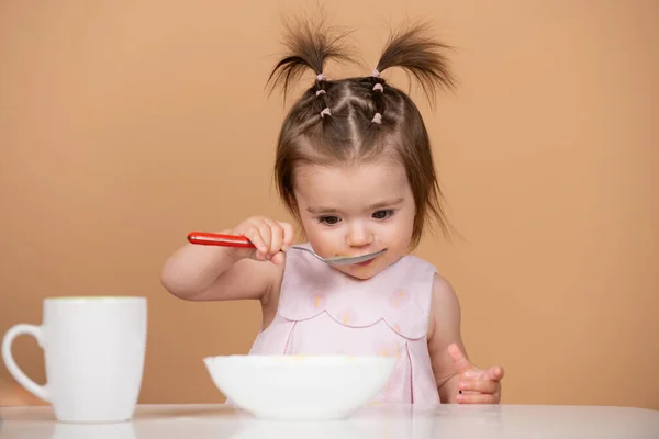 Portret van een schattig blank kind met lepel. Hongerige rommelige baby met bord na het eten van puree. Babyvoeding voor kinderen. — Stockfoto