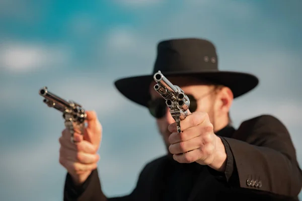 Sheriff in black suit and cowboy hat shooting gun, close up western portrait. Wild west, western, man with vintage pistol revolver and marshal ammunition. — Fotografia de Stock