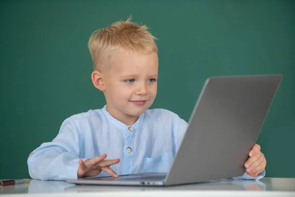 Školák se učí sedět za stolem a studovat online e-learning pomocí internetu. Geniální dětské programování, počítačový trénink. — Stock fotografie