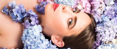 Makyaj malzemeleri ve cilt bakımı. Doğa güzelliği. Çiçeklerin üzerinde yatan kadın. Doğayla birlik. Çiçek. Ortanca çiçekli kız. Sancak bahar tasarımı, web sitesi başlığı reklamı.