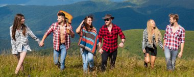 Dağda yürüyen mutlu arkadaşlar. Arkadaşlar bahar tatili afişi. Dağların tepesinde bir grup yürüyüşçü. Arkadaşlık özgürlüğü yaz tatili konsepti.