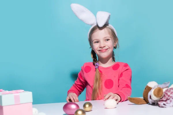Roztomilé děťátko s králičíma ušima o Velikonocích. Usmívající se dívka drží koš s malovanými vejci. — Stock fotografie