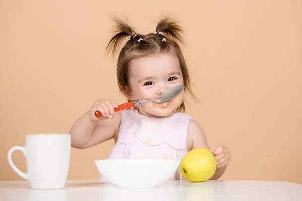 Bebés comiendo, comida saludable para un bebé. Primera comida de los bebés. El niño come solo con una cuchara y un plato. — Foto de Stock