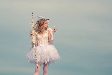 Güzellik gözlerini maviye boyadı. Güneş ışığında büyüleyici bir kadın. Oklu aşk tanrısı tatlı bir kız. Mutlu genç melek kız. Kıvırcık sarı saçlı melek kız. Güzel genç kız.