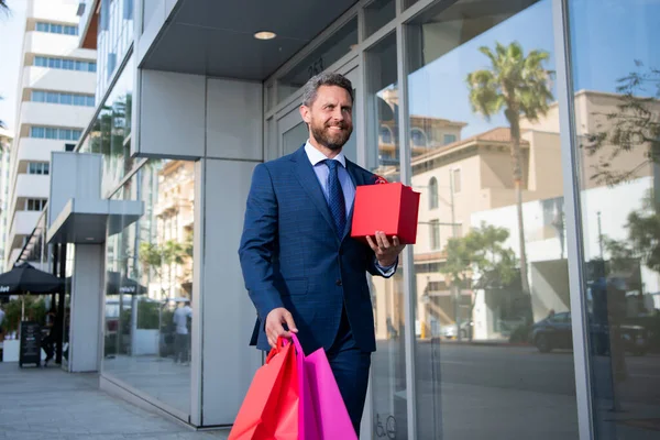 Uomo d'affari che trasporta borse della spesa, a piedi in città. — Foto Stock