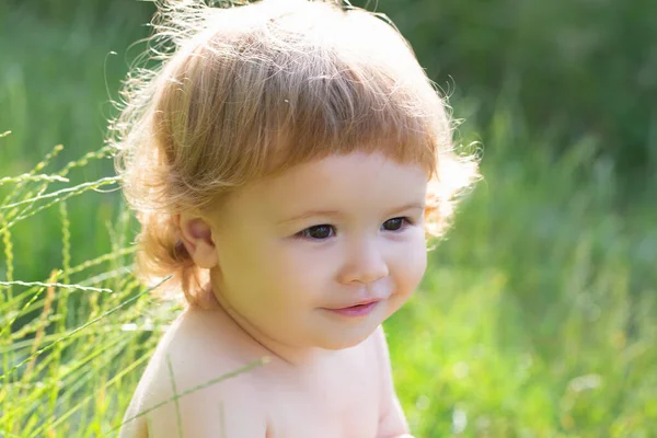 Leuke baby op groen gras in de zomer. Grappig kind van de natuur. Gelukkige kindertijd. Baby gezicht van dichtbij. Grappig kinderportret. Blond kind, emotie gezicht. — Stockfoto