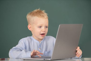 Okulda dizüstü bilgisayar kullanan küçük bir öğrenci. Küçük komik programcı..