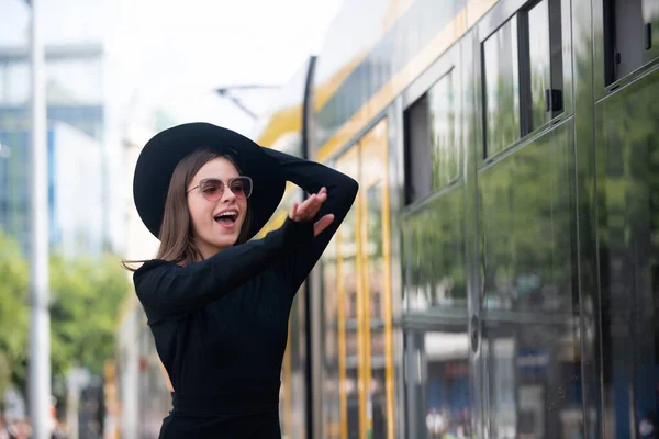 Foto de estilo de rua de mulher elegante moda vestindo roupas da moda correndo atrás trolleybus. Modelo que anda na rua da cidade europeia. Viajar na cidade. — Fotografia de Stock