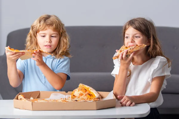 Niños comiendo pizza. Niños pequeños amigos, chico y chica muerden pizza. — Foto de Stock