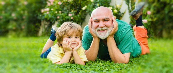 Child with Grandfather dreams in summer in nature. Portrait of happy senior and happy cute grandson. Grandfather and grandchild, spring banner. — Stock Photo, Image