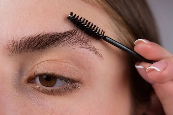 Eyebrow makeup. Woman brushing brows with brows brush closeup. Macro close up of brows. — Stock Photo, Image