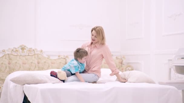Щаслива любляча сім'я. Мати і дитина син грають і обіймаються в спальні. День матері . — стокове відео