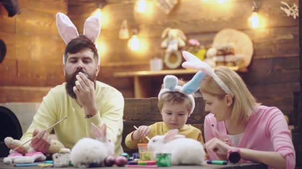 Familia de Pascua de madre, padre e hijo hijo pintaron huevos, usando orejas de conejo en el día de Pascua. Vacaciones familiares de primavera. — Vídeos de Stock