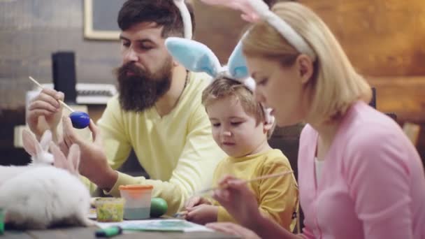 Pasen familie van moeder, vader en kind zoon geschilderd eieren, het dragen van konijnenoren op Paasdag. Familie viert Pasen met kinderen thuis. Familie vrije tijd. — Stockvideo