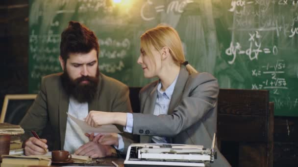 Retro stijl. Professor assisteren jonge vrouw houden boek tegen schoolbord in de klas. — Stockvideo