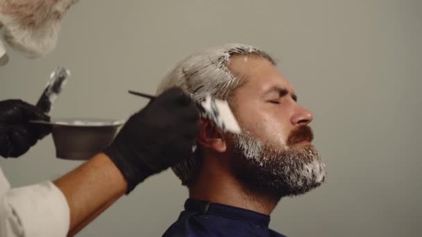 Profesionální kadeřník zbarvení mužské vlasy. Proces chlapské barvy vlasů v kadeřnictví. Barvení vlasů muž. Profesionální kadeřník umírající vlasy vousatý muž v salonu krásy, detailní záběr. — Stock video