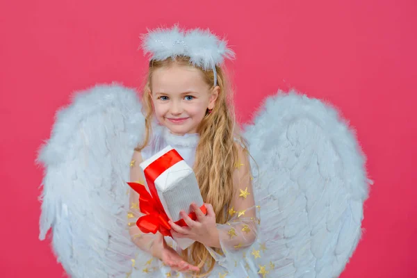 Geschenk kind emoties. Schattig engelenmeisje met engelenvleugels, geïsoleerd op rood. Valentijnsdag. Speels engelachtig klein meisje. — Stockfoto