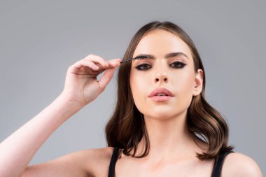 Kaş makyajı. Kaşlarını yakından fırçalayan bir kadın. İzole edilmiş kadın portresi.
