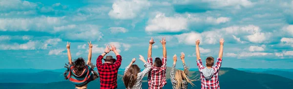 Amigos verano viaje bandera de vacaciones. Grupo de excursionistas con los brazos en la cima de la montaña, levantando las manos hacia el cielo. Amistad libertad verano vacaciones concepto. — Foto de Stock