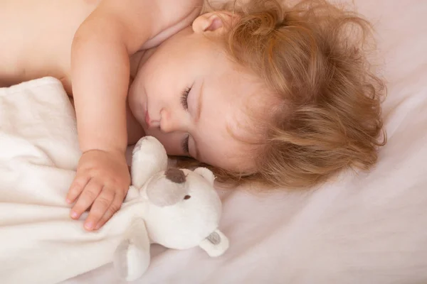 Vackert barn sover i sängen hemma med leksak, barn sover i sängen. — Stockfoto